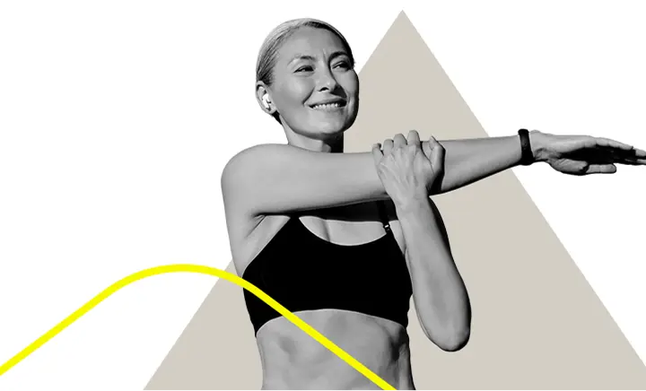 A woman smiling and holding her arm accross her chest to stretch.