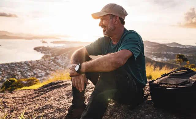 Man sitting hillside, overlooking a city.